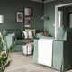 Modern green sofa in living room, large with cushions, below wall art, next to plant, with coffee table.