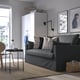 Modern living room with grey sofa, polka dot pillows, glass table, beige rug, light wood floor, white cabinet, wicker basket.