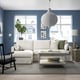 Modern living room with HYLTARP sofa in white, green pillows, wooden table, large window, grey rug, and hanging lamp.