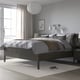 Minimalist bedroom with IDANÄS bed, light grey bedding, white curtains, pendant light, nightstands, large rug.