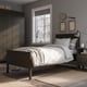 Modern minimalist bedroom an IDANÄS bed with light grey bedding, dark wooden wardrobe, beeswax-colored rug, and decorative tennis racket.