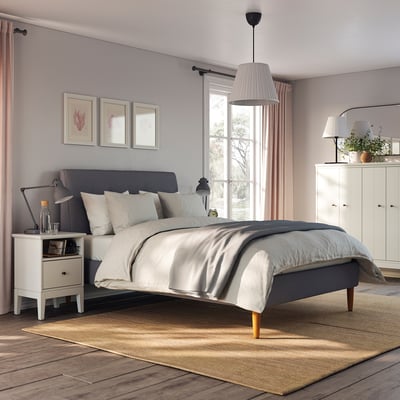 Modern bedroom with IDANÄS grey upholstered bed, white bedside table, large window, and pendant light.