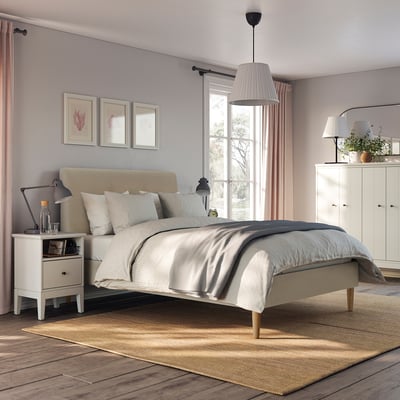 Bedroom with beige IDANÄS bed, nightstands, lamps, and plants.