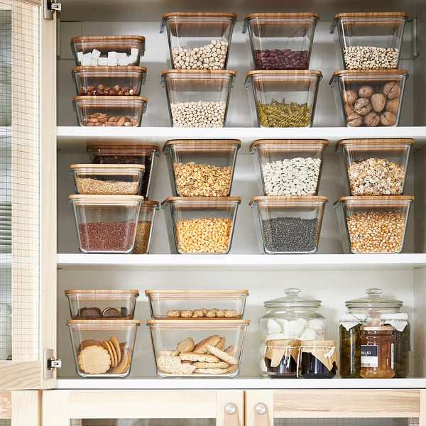 Organised kitchen shelf with IKEA 365+ containers for dried foods, bamboo lids, some as coasters.