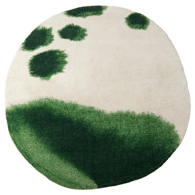 Round, green-and-white rug with organic spots, made from polypropylene and synthetic rubber.