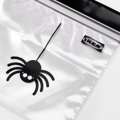 Black spider decoration in clear plastic bag with IKEA branding.