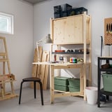 Wooden craft room with IVAR shelves, supplies, stool, easels, pegboards.