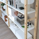 Bookshelf with books, a clock, sunglasses, shoes, and decorative items.