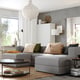 Modern living room with grey JÄTTEBO modular sofa, colourful pillows, woven rug, large window, and stylish decor.