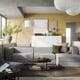 Modern living room with grey JÄTTEBO modular sofa, mustard walls, white decorative lights, and cosy textiles.