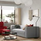 Modern living room with grey JÄTTEBO sofa, red chair, wooden cabinets, coffee table, plant, and hanging lamp.