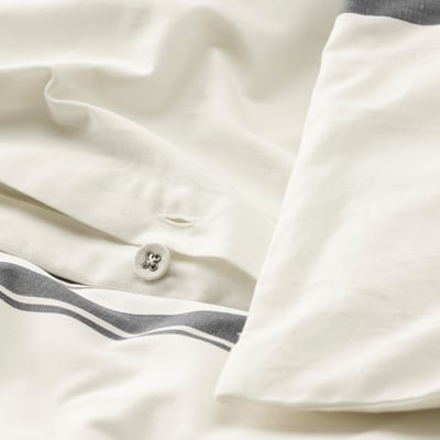 Close-up of crisp white pillowcase with grey stripes. Button detail in centre, indicating easy fastening. Part of JÄTTEFRÄKEN bedding.