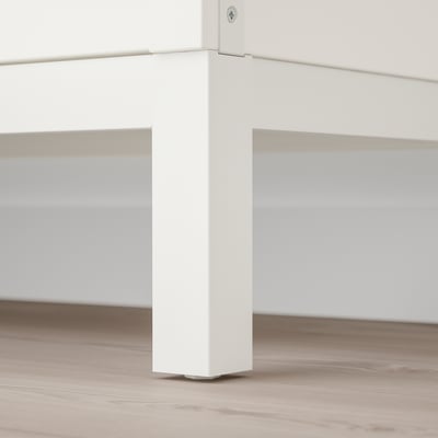 Close-up of a KALLAX shelf leg, showcasing its sturdy, white metal construction and subtle, adjustable foot for stability.