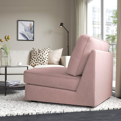 A compact sofa-bed in a living room, featuring a light pink cover with a modern design, perfectly suited for small spaces and versatile use.