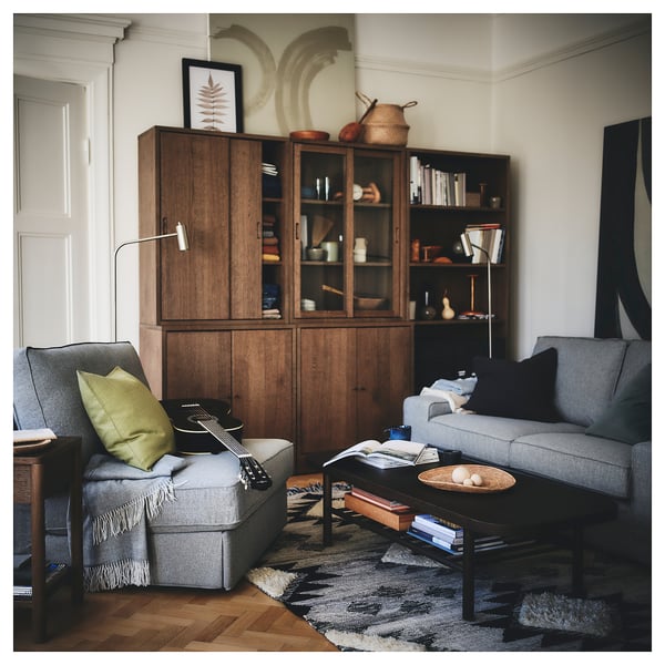 Modern living room with grey KIVIK sofa, wooden bookcases, black coffee table, and decorative items.