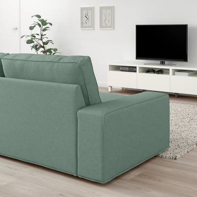 Minimalist living room with turquoise sectional sofa, tv, and plant.