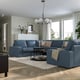 Modern living room with blue KIVIK sectional, white chandelier, grey rug.