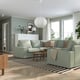 Modern living room: large KIVIK sofa in light green with wooden coffee table. Large windows with curtains, striped rug, and pendant light.
