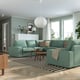 Modern living room with KIVIK green sectional, striped rug, wooden table, and hanging light.