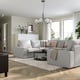 Modern living room with large KIVIK grey sofa, light wood floor, white walls, and large windows. Sofa is spacious and inviting with multiple cushions.