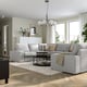 A spacious living room with a grey KIVIK sofa, soft pillows, and a rug, with large windows and a chandelier.
