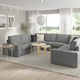 Modern living room with KIVIK sectional sofa, rug, tables, plant, and natural light.
