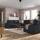 Modern living room with KIVIK sectional, wooden tables, pink walls, large windows, white cabinet.