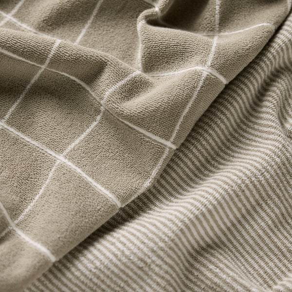 Folded beige towels with square grid pattern and wavy stripes, soft texture.