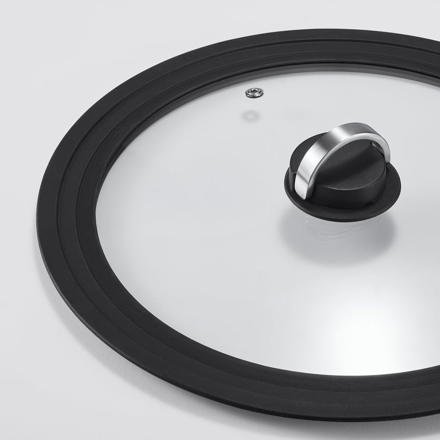 Clear, round glass pot lid with black silicone rim, steam vent, and foldable metal handle.