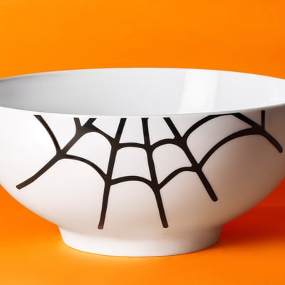 White bowl with black geo pattern on orange surface.