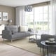 Modern living room with grey LÅNGARYD sofa, glass coffee table, and large window. Sofa is large, comfortable, with a sleek design.