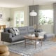 Modern living room with grey sofa, wooden table, and pendant light. Large windows and plants enhance brightness and comfort.