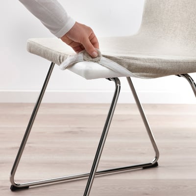 Person adjusting LILLÅNÄS chair cover, showing removable for washing.