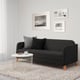 Modern living room with LINANÄS black sofa, grey pillows, white side table, and three framed photos on the wall.