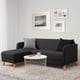 Modern living room: black LINANÄS sofa in corner, white coffee table, grey pillows, wall art, light rug.