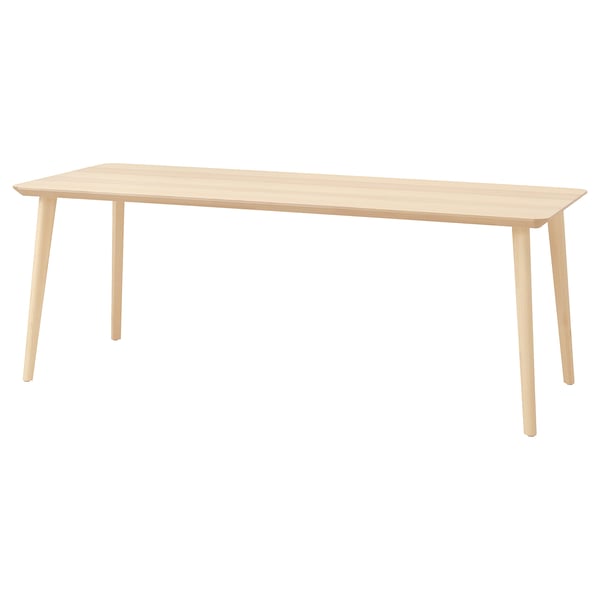 A light-colored wood rectangular dining table. It has a sleek design with angular legs, making it perfect for modern spaces.