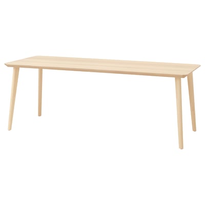 A light-colored wood rectangular dining table. It has a sleek design with angular legs, making it perfect for modern spaces.