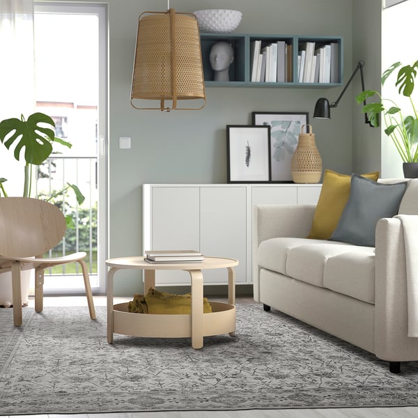 Modern living room with a beige LOKALTÅG rug, light grey sofa, wooden coffee table, and a large window letting in natural light.