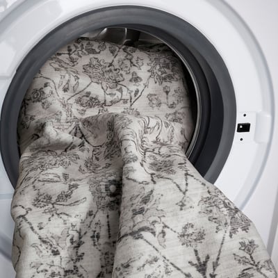 A white dryer with a patterned blanket inside, partly hanging out.