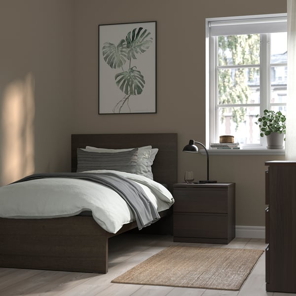 Modern, cosy bedroom with brown MALM bed and white bedding, grey bedside table with lamp, art print, and plant on the window.
