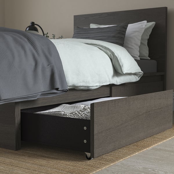 A modern bedframe with a drawer open, showing storage below. The headboard and a cosy bed setup are visible.