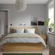 Modern bedroom with MALM bed, storklinta bedside table, white lamp, photos, and green plant.