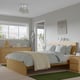 Modern, minimalist bedroom with grey-blue bed linens, wooden MALM bed & dresser, grey walls, and a large window.