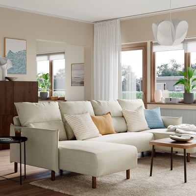 A modern living room with a MANNARP sectional sofa. Cream-colored, plush, and spacious with wooden furniture and a rug.