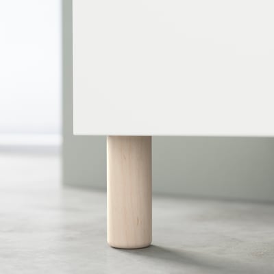 Round wooden table leg, lightly stained, supporting white table.