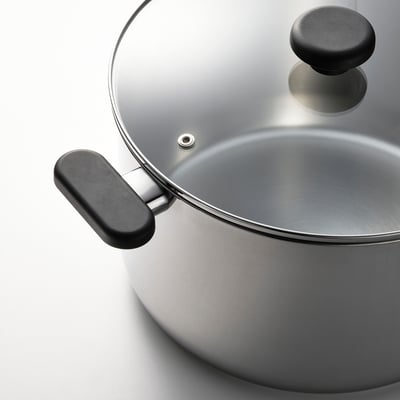 Silver saucepan with black handles and a clear glass lid, showcasing its sleek, modern design and durable construction.