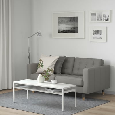 Contemporary living room with MORABO sofa, coffee table, lamp, and art. Sofa has cushions and pillows. Table holds a cup and vase.
