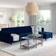 Modern living room with deep blue tufted sectional sofa, soft lighting, and glass coffee table.
