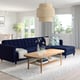 Modern living room with navy sofa, wooden table, and large windows. Minimalist decor, natural light.