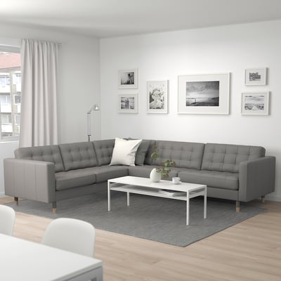 Modern living room with grey MORABO sectional sofa, white pillow, coffee table, and grey/white decor. Bright, spacious, and well-lit.